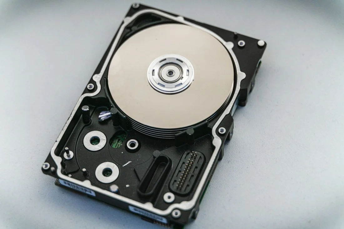 An opened mechanical hard drive showing its platter and read head